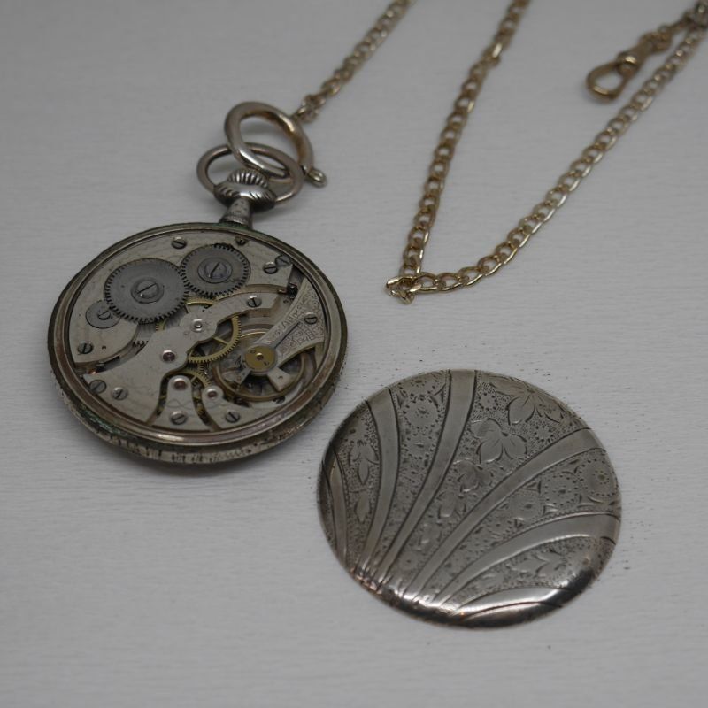 alt=\"Reloj antigüo de bolsillo caballero con cadena y caja de plata de ley marca Gentileza en estado de marcha\"